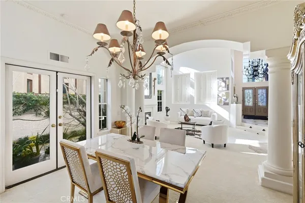 a view of a dining room with furniture a chandelier and large windows