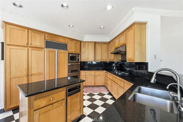 a kitchen with granite countertop a sink a counter top space cabinets and stainless steel appliances