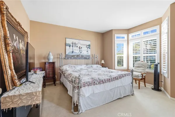 a bedroom with a bed couch and a flat tv screen next to a window
