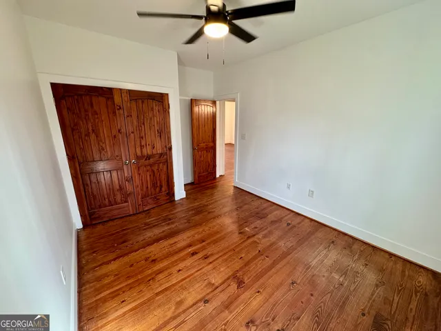 an empty room with wooden floor closet and windows