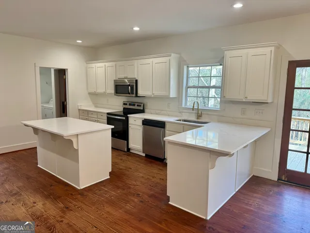 a kitchen with stainless steel appliances granite countertop a stove top oven a sink a refrigerator and white cabinets