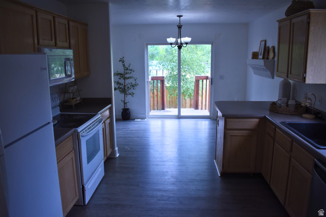 3327 East Windhover Road Eagle Mountain, UT 84005 - Photo 11 of 38 Kitchen featuring wood-finish flooring, light wood cabinetry, white appliances, and a sliding glass door leading to an outdoor deck with wood railings