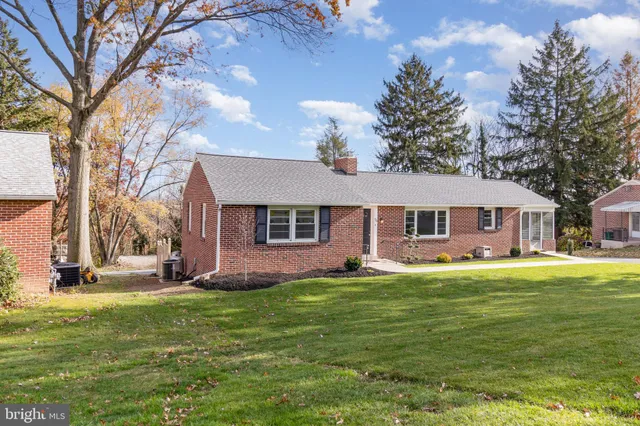 a front view of a house with a garden and trees