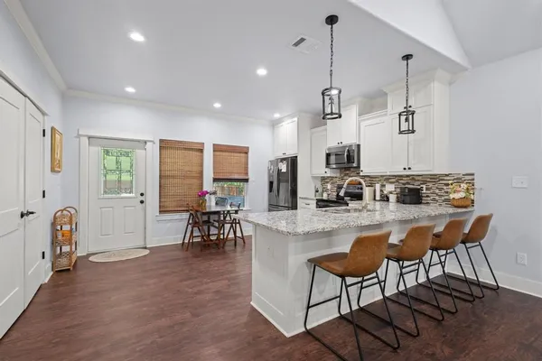 a kitchen with stainless steel appliances granite countertop sink stove and white cabinets with wooden floor