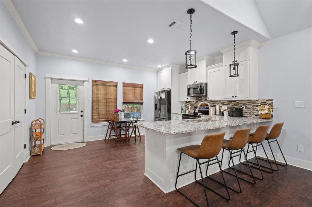 610 West Elm Street Denison, TX 75020 - Photo 8 of 26 a kitchen with stainless steel appliances granite countertop sink stove and white cabinets with wooden floor