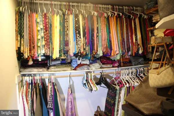 a view of walk in closet with clothes and shoes