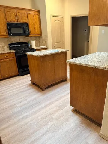 a kitchen with stainless steel appliances wooden floor and a refrigerator