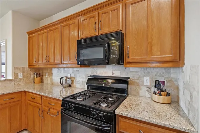 a kitchen with granite countertop stainless steel appliances a stove a sink dishwasher and cabinets with wooden floor