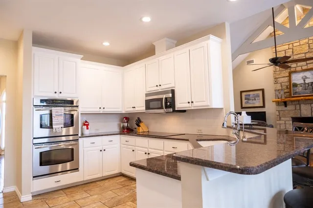 a kitchen with kitchen island granite countertop a sink a stove and cabinets