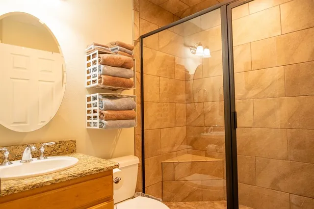 a bathroom with a granite countertop sink a toilet and shower