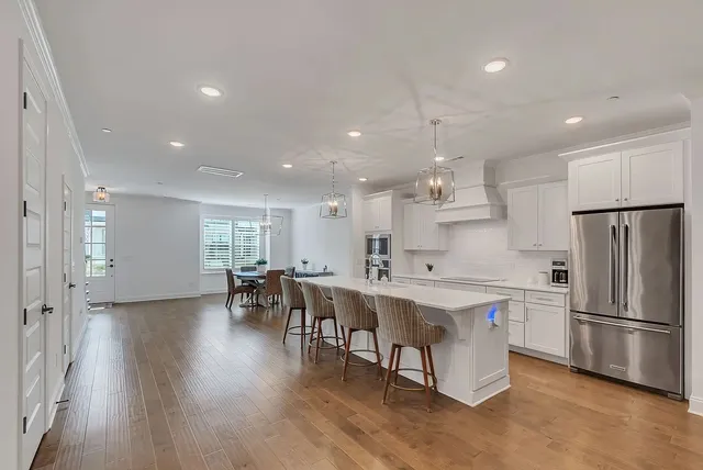 a kitchen with stainless steel appliances a table chairs wooden floors and a view of living room