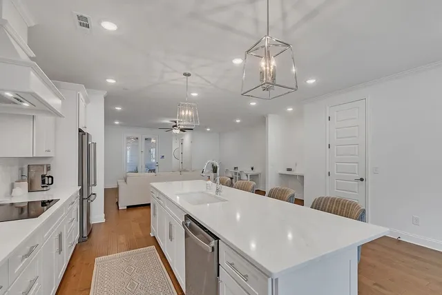 a large white kitchen with a large center island sink and stainless steel appliances