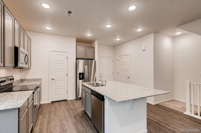 a kitchen that has a lot of cabinets a sink and wooden floor