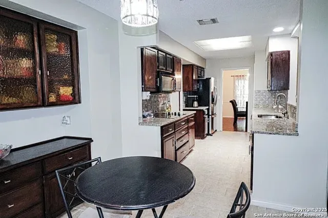 a kitchen with stainless steel appliances kitchen island granite countertop a sink a refrigerator a stove a dining table and chairs