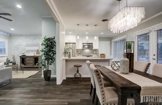 a very nice looking dining room with kitchen island furniture a chandelier a large kitchen island and stainless steel appliances