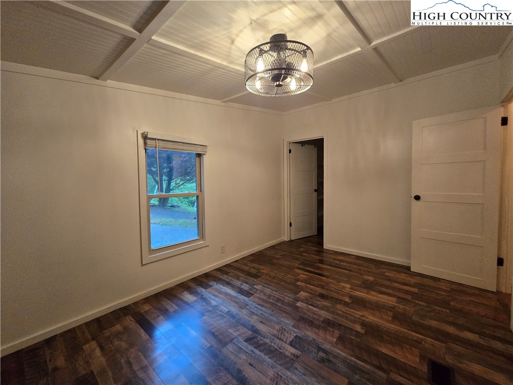 618 Rhymer Branch Road Deep Gap, NC 28618 - Photo 18 of 24 an empty room with wooden floor chandelier and windows