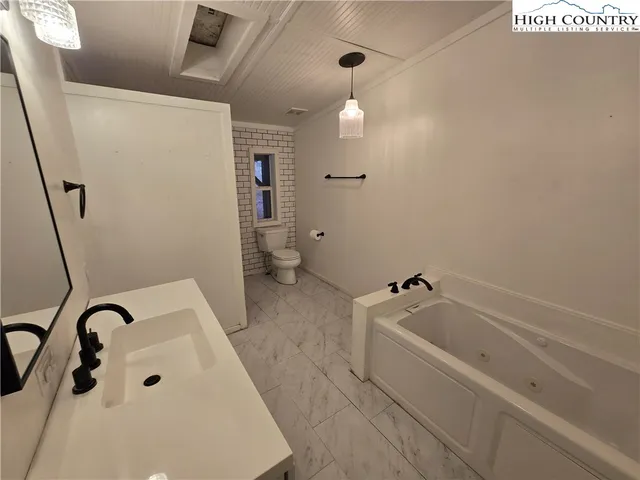 a bathroom with a tub a sink and a large mirror