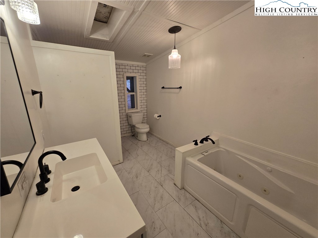 618 Rhymer Branch Road Deep Gap, NC 28618 - Photo 10 of 24 a bathroom with a tub a sink and a large mirror