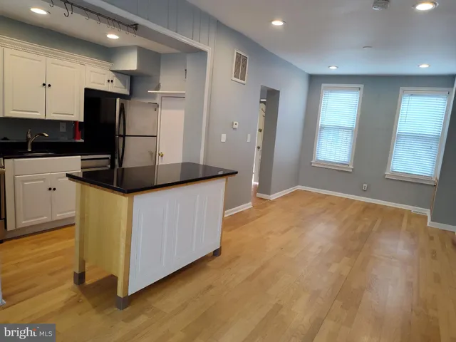 a kitchen with kitchen island a sink a stove a refrigerator and white cabinets