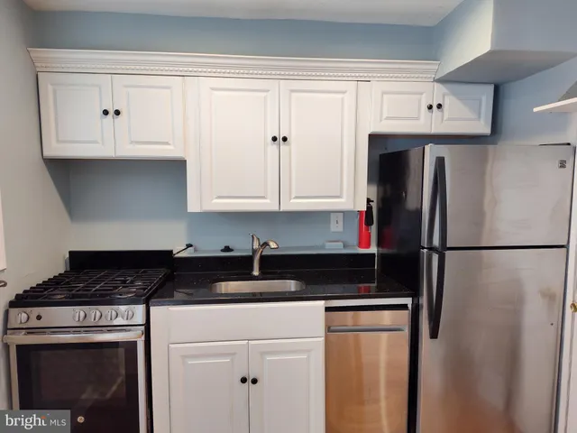 a kitchen with a refrigerator and white cabinets