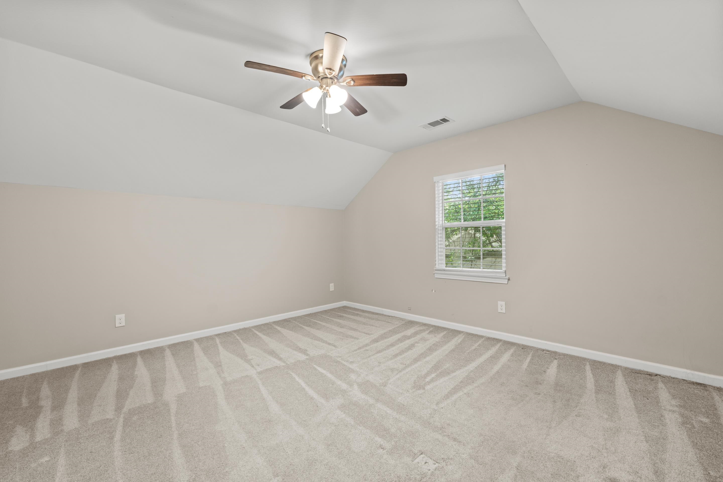 1255 Colonial Road Memphis, TN 38117 - Photo 22 of 30 Spacious room featuring vaulted ceilings, a ceiling fan with integrated lighting, neutral wall tones, light-toned carpeting, and a window with blinds