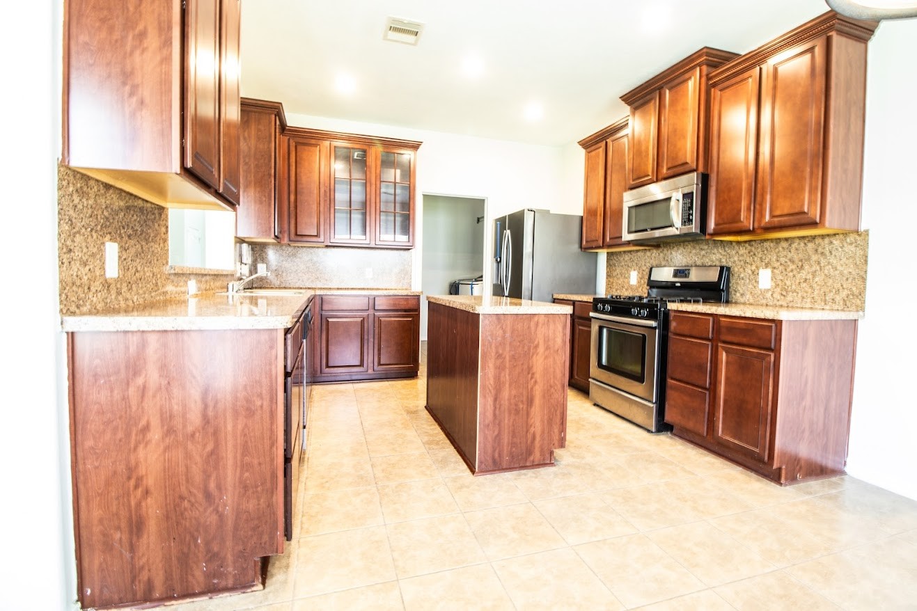 21218 Branchport Drive Houston, TX 77095 - Photo 3 of 18 a kitchen with stainless steel appliances granite countertop a stove top oven a sink dishwasher and wooden cabinets