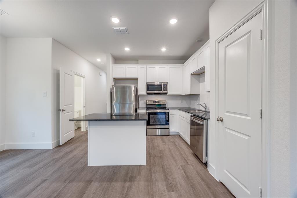 412 East 7th Street, Unit 2 Bonham, TX 75418 - Photo 3 of 12 a kitchen with stainless steel appliances granite countertop a refrigerator a stove top oven a sink and dishwasher with wooden floor