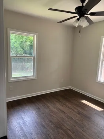 a view of an empty room with wooden floor and a window