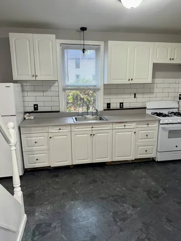 a kitchen with granite countertop a sink a stove and cabinets