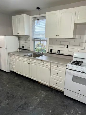 a kitchen with granite countertop white cabinets and white appliances