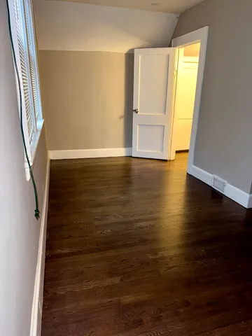 a view of an empty room with wooden floor and stairs