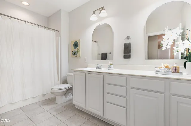 a bathroom with a double vanity sink a toilet and a mirror