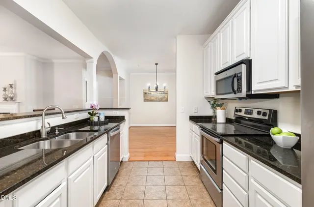 a kitchen with granite countertop stainless steel appliances a sink a stove top oven and cabinets