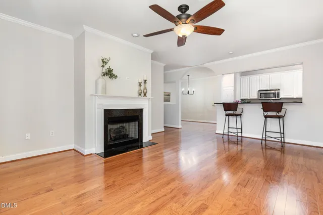 an empty room with wooden floor a ceiling fan a fireplace and windows