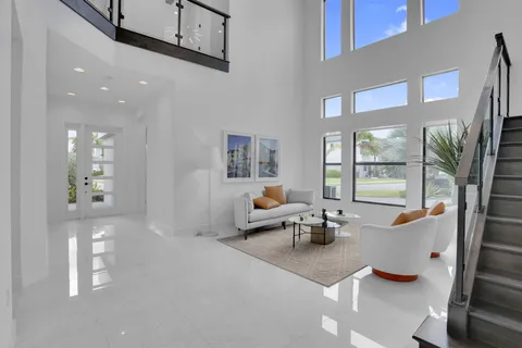 a living room with furniture floor to ceiling window and a kitchen