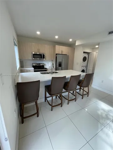 a living room with stainless steel appliances furniture a flat screen tv and kitchen view