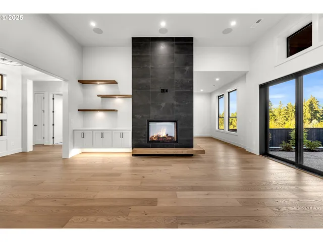 a view of an empty room with window and wooden floor