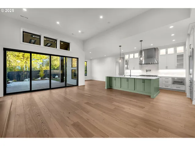 a view of an empty room with kitchen view and a large window