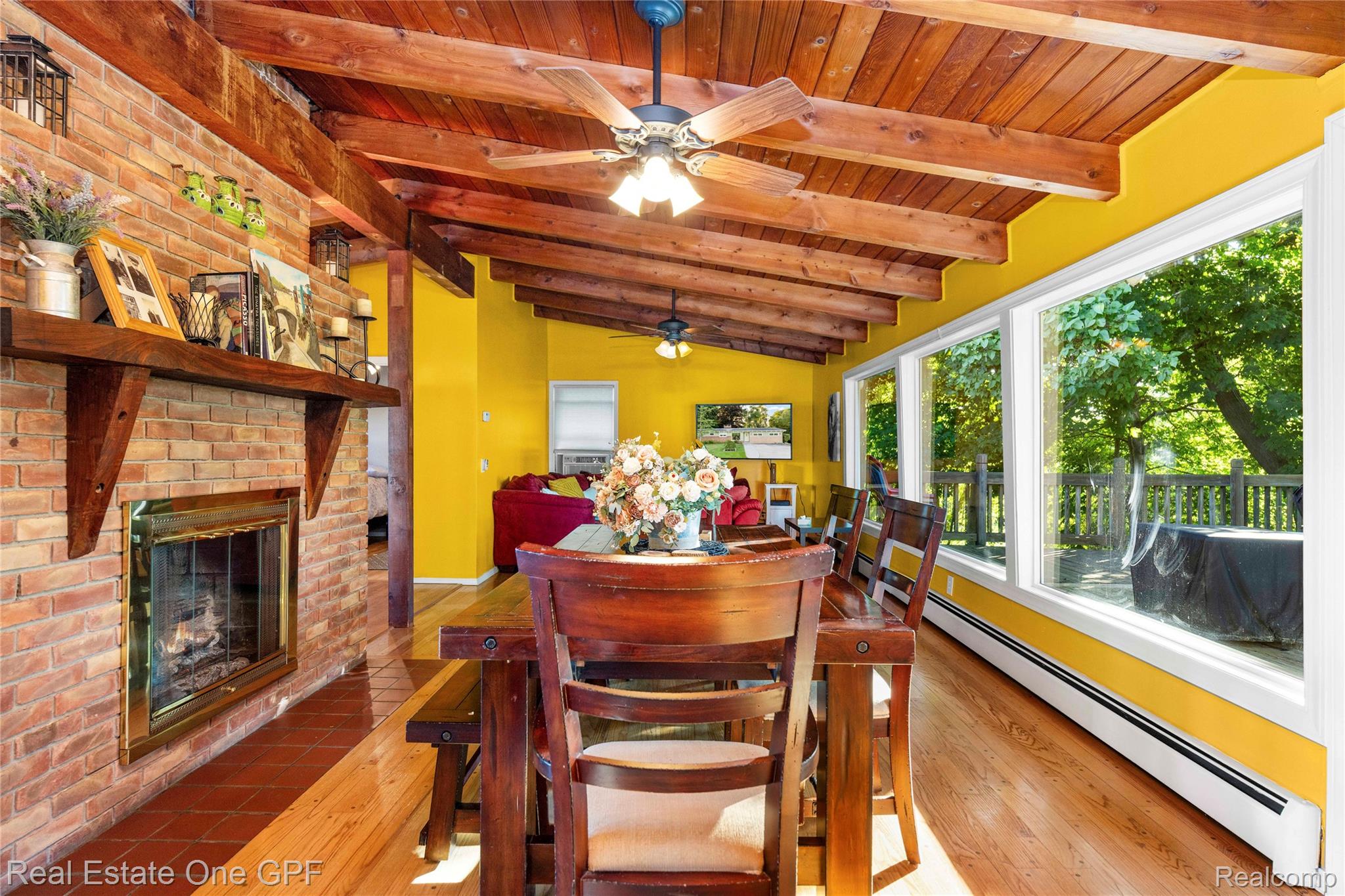 5068 Atkins Road North Street, MI 48049 - Photo 19 of 78 Vaulted wood-beam ceiling, brick fireplace with a wood mantle, wood-finish flooring, and a wall of picture windows