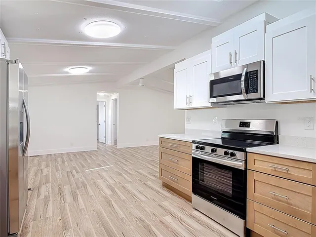 a kitchen with stainless steel appliances a stove a microwave oven cabinets and a wooden floor