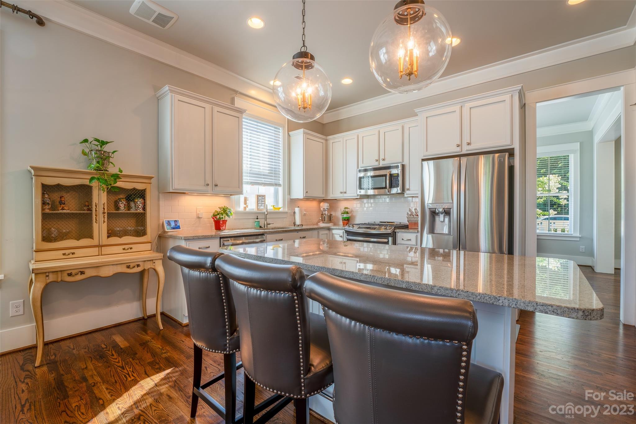 724 Bluff Loop Road Rock Hill, SC 29730 - Photo 3 of 45 a kitchen with stainless steel appliances granite countertop a stove refrigerator a sink dishwasher a dining table and chairs with wooden floor