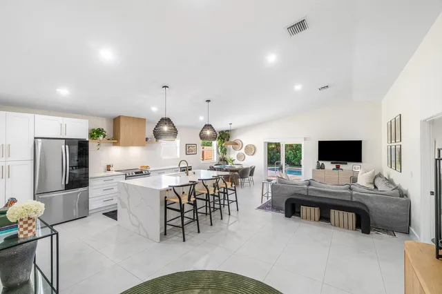a living room with furniture a flat screen tv and a refrigerator