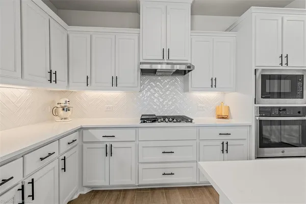 a kitchen with white cabinets and stainless steel appliances