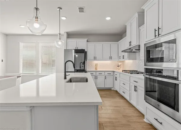 a kitchen with kitchen island white cabinets stainless steel appliances and a window