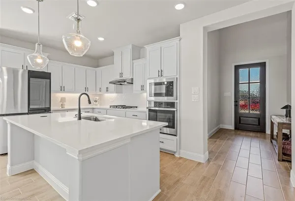 a kitchen with kitchen island a sink appliances and cabinets
