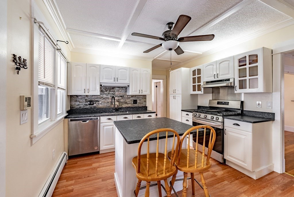 48 Rimmon Avenue Chicopee, MA 01013 - Photo 4 of 41 a kitchen with stainless steel appliances granite countertop a stove top oven a refrigerator a sink dishwasher a dining table and chairs with wooden floor