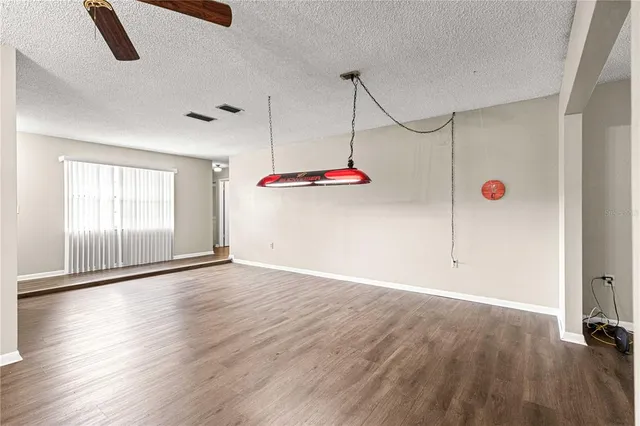 a view of an empty room with wooden floor and windows