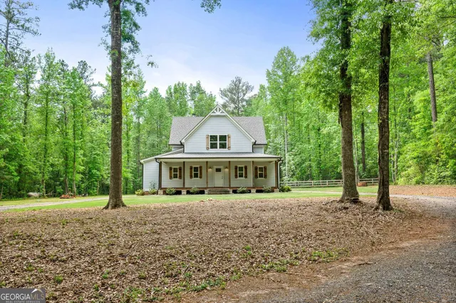 a view of a white house with a big yard and large trees