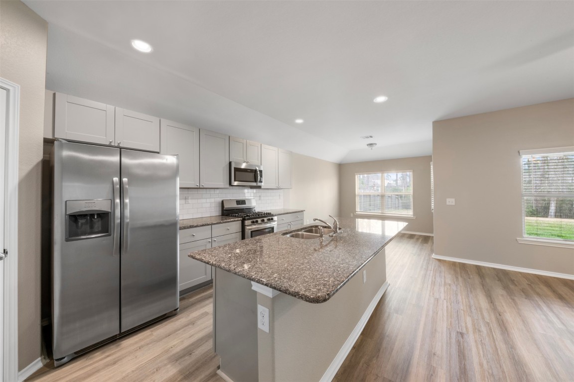 175 Courageous Side Way Magnolia, TX 77354 - Photo 10 of 28 a kitchen with kitchen island granite countertop stainless steel appliances a sink stove refrigerator and cabinets