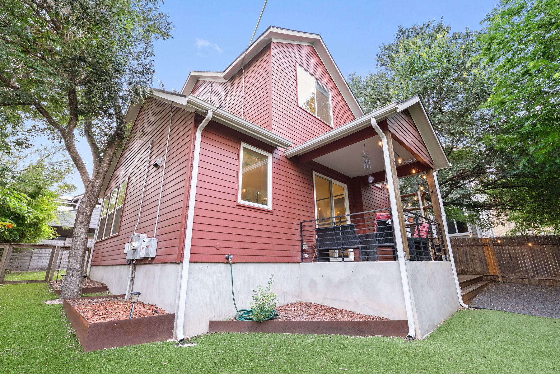 1709 Perez Street, Unit 2 Austin, TX 78721 - Photo 31 of 33 A charming red-sided dwelling offers a private deck, nestled amongst verdant trees and a well-kept yard.